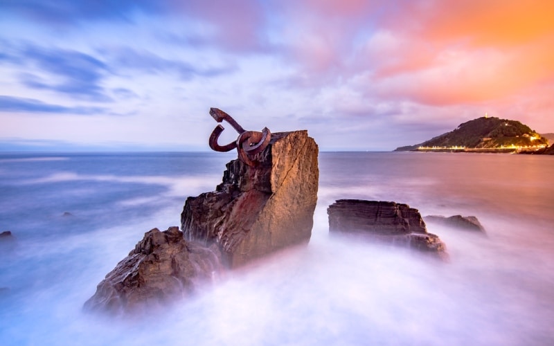 Una escultura de acero en unas rocas sobre el mar