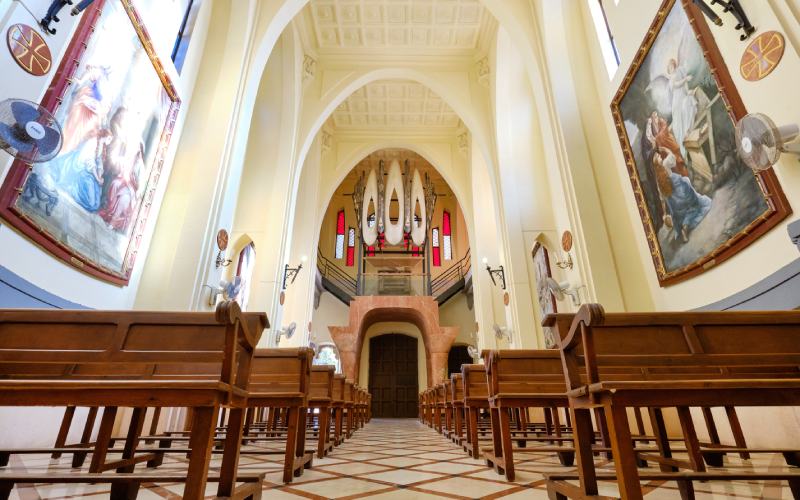 Pasillo entre bancos de madera que conduce al órgano de tubos en el interior del Santuario de Santa María Magdalena